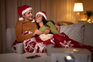 Noel arifesinde, bir çift kanepeye oturup Noel Baba şapkası takar ve birlikte film gecesinin tadını çıkarırlar. Battaniyeye sarılıp patlamış mısırlarını ve evlerinde rahat anlarını paylaşıyorlar..