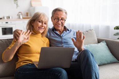 Yaşlı bir çift kanepede yan yana oturur ve neşeli bir görüntülü konuşma sırasında dizüstü bilgisayarlarına gülümser ve el sallarlar. Işıl ışıl, rahat oturma odaları anlarının sıcaklığını arttırıyor..