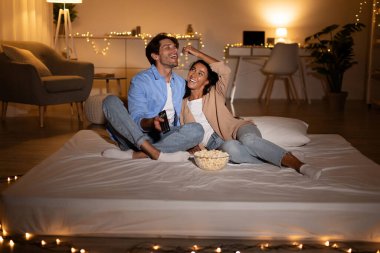 Mutlu bir çift, sıcak oturma odalarında bir şiltede oturur, patlamış mısırlarını paylaşır ve film izlerken birlikte gülerler. Hafta sonu boyunca huzurlu bir akşamdan hoşlanırlar..