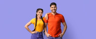 İki arkadaş gülümseyerek yan yana durur. Biri sarı gömlek ve diğeri kırmızı gömlek giyiyor. Mor bir arka plana karşı birlikte eğlenceli bir anın tadını çıkarıyorlar..