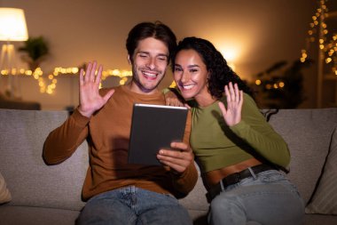 Eşler evlerindeki koltuklarında oturup videolar çekilirken mutlu bir şekilde dijital tablete el sallıyorlar. Işıklar, çevrimiçi iletişim kurdukları ve birlikte vakit geçirdikleri rahat bir atmosfer yaratıyor..