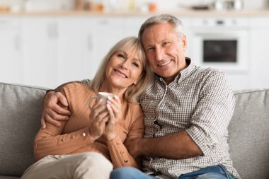 İki son sınıf öğrencisi kanepede yan yana otururken sıcak bir içki içerler. Parlak oturma odası sakin bir öğleden sonra neşe dolu bir atmosfer yaratır..