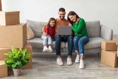 Neşeli bir Orta Doğulu aile yeni evlerindeki bir kanepede oturur, mobilyaları ve dekorları tartışmak için dizüstü bilgisayar kullanır, bu arada kutular ve bitkilerle çevrilidir. Birlikte iyi vakit geçiriyorlar..