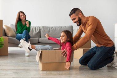Neşeli bir Orta Doğulu aile yeni evlerinde taşınma gününü kutluyor. Baba kızını karton bir kutunun içinde gezdirirken anne kanepeden gülümseyip birlikte güzel anılar yaratıyor..