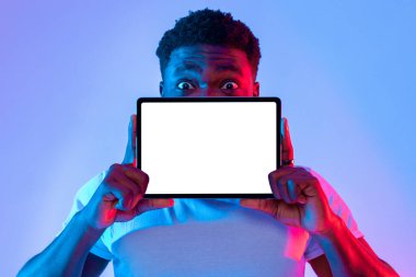 Genç bir adam, elinde boş bir tabletle güvenle ayakta duruyor. Sahne canlı mavi ve pembe ışıklandırmayı içeriyor, dikkat çeken çekici bir atmosfer yaratıyor..