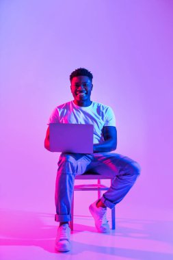 Neşeli bin yıllık siyahi adam bir sandalyede oturur, bir dizüstü bilgisayarla çalışır ya da uzak bir görüşmeyle meşgul olur. Renkli neon ışıklar çalışma alanında canlı bir atmosfer yaratıyor..