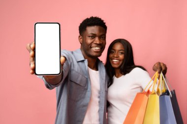 Neşeli siyah bir çift, renkli alışveriş torbalarıyla çevrili, yakında duruyor. Boş ekranlı bir cep telefonu sergiliyorlar. Pembe bir stüdyoda yeni bir alışveriş uygulaması önermekten heyecan duyuyorlar..