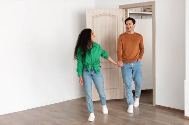 Heyecanlı kadın erkeğin elini tutuyor ve onu parlak, modern bir oturma odasına götürüyor. Neşeli bir anı paylaşıyorlar, sıcak atmosferde yeni evlerini keşfediyorlar..