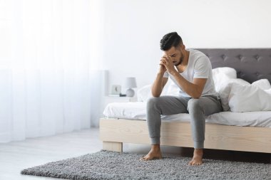 Evdeki yatağın kenarında oturan depresif genç bir Arap 'ın portresi. Kafasını ellerinin üzerine yaslıyor, sakin bir ortamda yalnızlık ve kalp kırıklığını yansıtıyor..