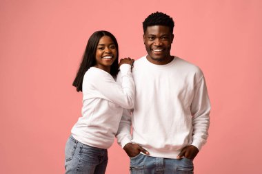 Canlı pembe bir stüdyo geçmişinde, neşeli bir Afrikalı Amerikalı çift mutlu poz veriyor. Erkek ve kadın aynı beyaz tişörtü ve kot pantolonu giyer, aşk dolu bir anı paylaşırlar..