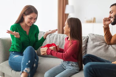 Genç Arap kız, heyecanlı ve neşeli görünen annesine bir hediye sunar. Mutlu bir aile olarak, sıcak bir oturma odasında özel bir günün tadını çıkararak kutluyorlar..