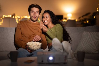 Çift rahat bir oturma odasında rahat bir şekilde oturur ve projektörlü bir film izler. Patlamış mısır ve kahkahayı paylaşıyorlar, birlikte güzel vakit geçiriyorlar..