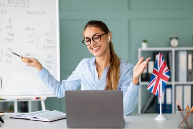 Dost canlısı bir öğretmen uzaktan ders sırasında İngilizce dil bilgisi kurallarını açıklar. Öğrencilerle masasında otururken bir web kamerası aracılığıyla iletişim kuruyor, aktif olarak kanalı için ders veriyor ve kayıt yapıyor..