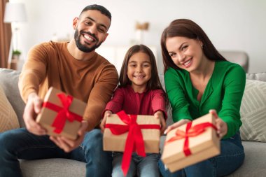 Sevgi dolu bir Orta Doğulu aile oturma odasındaki bir kanepede oturuyor, ellerinde paketlenmiş hediye kutularıyla. Birlikte bir bayramı kutluyorlar, gülümseme ve kahkahalarla özel bir an yaratıyorlar..