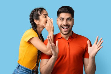 Genç bir adam heyecan gösterirken bir kız kulağına bir şeyler fısıldıyor. İkisinin de neşeli ifadeleri var, neşeli ve neşeli bir atmosfer yaratıyorlar..