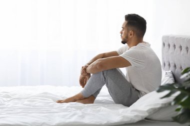 Yumuşak ışıklı bir yatak odasında, genç bir Orta Doğulu adam yatakta oturuyor, ifadesi düşünceli ve melankolik. Bir anlık yalnızlık anında duygularını yansıtarak gözlerini kaçırır..