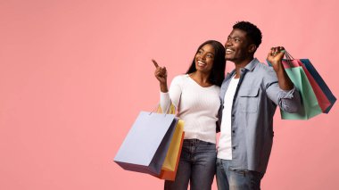 İki Afro-Amerikan aşığı ellerinde alışveriş torbalarıyla mutlu mesut geziyorlar. Fotokopi alanını gösteriyorlar, birbirlerine gülümsüyorlar ve pembe bir arkaplanda kameraya bakıp birlikte geçirdikleri zamanın tadını çıkarıyorlar..