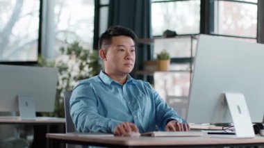 Çağdaş bir ofiste masa başında oturan bir adam işine konsantre oluyor. Parlak doğal ışık büyük pencerelerden süzülerek atmosferi güçlendirir..