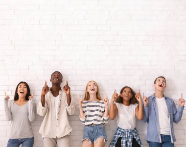 Vay canına, şuna bak. Bir grup çok ırklı heyecanlı arkadaş beyaz tuğla duvarın üzerindeki fotokopi alanını işaret ediyor.