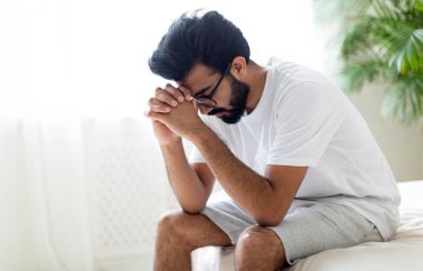 İktidarsızlık kavramı. Evde yatağında oturan endişeli, üzgün, genç Hintli adam Ereksiyon Bozukluğu çeken, yatak odasında dinlenen, sağlık sorunlarını düşünen, fotokopi çeken