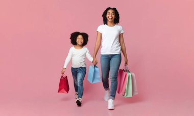 Mutlu Afrikalı Amerikalı Anne ve Kızı Pembe Arkaplanda Parlak Alışveriş Torbalarıyla Geziniyor