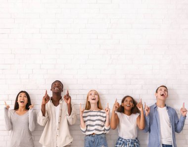 Vay canına, şuna bak. Beyaz tuğla duvarın üzerinde fotokopi alanını gösteren çok ırklı heyecanlı arkadaşlar grubu