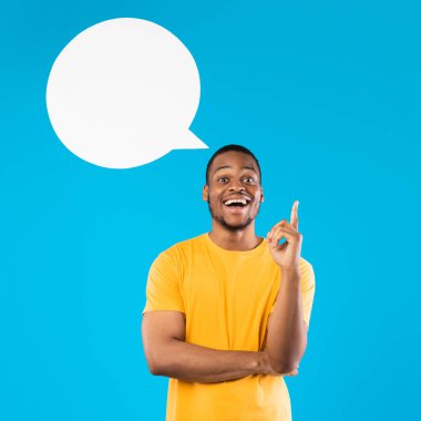 Harika bir fikir. Mavi Stüdyo Arkaplanı 'nın üzerinde duran kameraya gülümseyen boş konuşma baloncuğuyla parmağını havaya kaldıran heyecanlı siyahi adam. Eureka Anı, İlham Konsepti. Kare