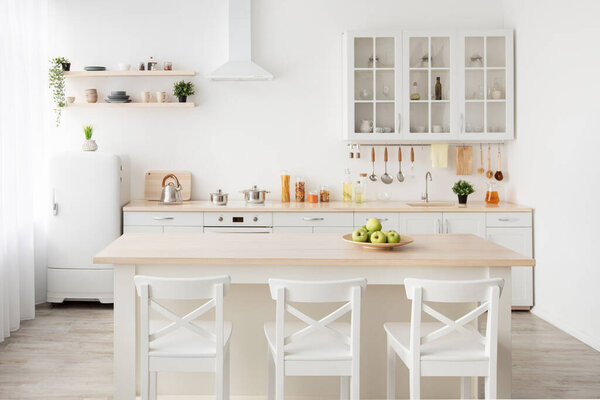 Скандалы с интерьером и кухней столовой, арендой, рекламой и продажей квартиры. Стол, стулья, посуда на мебели и полках, холодильник возле окна, светлые стены