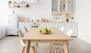 Çeşitli aksesuarlarla modern İskandinav mutfağı. Raflarda ev eşyaları olan beyaz mutfak mobilyaları ve ahşap masa, panorama