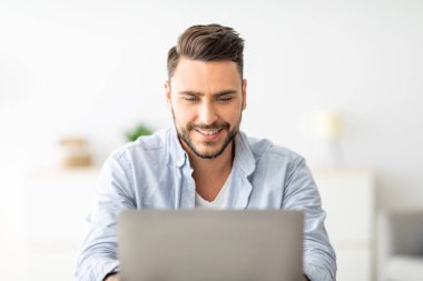 Merkez ofis konsepti. Bilgisayarda çalışan mutlu adamın yakın plan portresi, iç mekandaki iş yerinde oturuyor. Heyecanlı erkek öğrenci bilgisayar, öğrenim ve eğitim kullanıyor