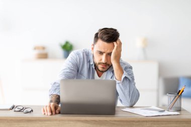 Bağımsız stres. Erkek serbest yazar işten sonra evde dizüstü bilgisayar başında yorgun, projeyle ilgili sorunları var, iş yerinde ev ofisinde oturuyor, boş yer var.