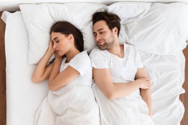 Evli bir çiftin evde yatakta yatışının görüntüsünün üzerinde. - Evet. Genç eşler konforlu yatak odasında dinleniyor. Sağlıklı uyku, iyi uykular. Sağlık ve Rahatlama Konsepti