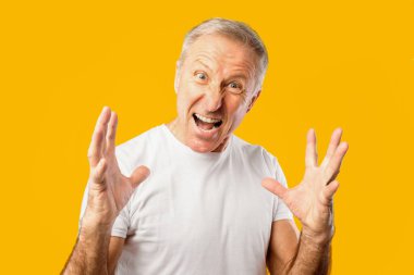 Bir adam duygularını canlı bir yüz ifadesi ve parlak sarı bir arkaplan önünde el hareketleriyle gösterir. Düşüncelerini tutkuyla paylaşıyor gibi görünüyor..