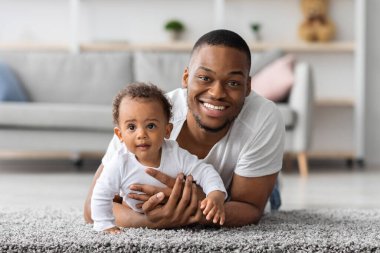 Yakışıklı, genç, siyah bir babanın evde güzel bir bebekle portresi, Afrikalı bir Amerikalının tatlı çocuğuyla poz verirken oturma odasında dinlenmesi, boş bir alan.