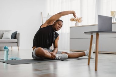 Sportif Afro-Amerikalı Adam dizüstü bilgisayarla evde egzersiz yaparak yan bükme egzersizi yapıyor. Erkek Fitness Antrenmanı Motivasyonu, Yurtiçi Eğitim Konsepti. Seçici Odaklanma