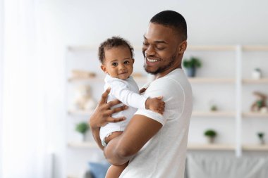 Mutlu Afrika kökenli Amerikalı baba, sevimli yeni doğmuş bebeğini kucaklıyor, siyah babayı seviyor, tatlı bebekle vakit geçiriyor, ona sarılıyor, babalık izninin tadını çıkarıyor, boşluğu kopyalıyor.