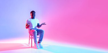 Neşeli bir Afro-Amerikalı adam gündelik bir şekilde sandalyede oturuyor ve şirketleri bedava reklam alanından yararlanmaya davet ediyor..