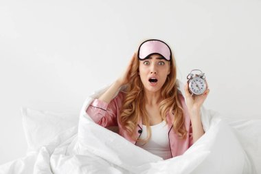 Bu kadar geç kalkmak. Uyuyakalmak, işe geç kalmak, endişe. Şok olmuş, pijama giymiş, elinde alarmlı saatle beyaz duvar arkasında uyuyakalmış sarışın bir kadın.