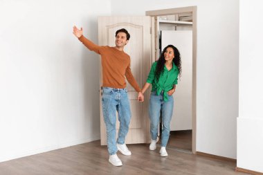 Mutlu adam, bir kadının yeni modern dairesine girmesi için işaret eder. El ele tutuşup gülümsüyorlar ve karşılama salonunu birlikte keşfediyorlar..