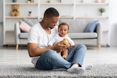Mutlu, genç, siyah bir baba, tatlı küçük oğluyla evde oynuyor, Afrikalı Amerikalı babayı seviyor, babalığı seviyor, sevimli küçük çocukla oturma odasında vakit geçiriyor, boş bir alanda yaşıyor.