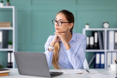 Genç bir iş kadını ofisteki masasında oturup dizüstü bilgisayarından gözlerini kaçırarak hayal kuruyor. Düşünceli bir an geçiriyor, modern çalışma alanındaki çevrimiçi görevlerine ara veriyor..