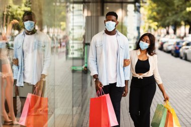 Yeni Normal Kavram. Sıradan bir Afro-Amerikan çiftin portresi. Tıbbi maske takıyorlar. Alışveriş merkezinin yakınından geçiyorlar.