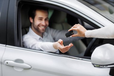 Tanınmayan araba satıcısı ve araba alan adam. Satıcı, bayilik salonunun yeni sahibine anahtarı veriyor. Kadın gülümseyen milenyum Avrupalı yakışıklı bir adama anahtar veriyor, seçici odaklı, bulanık