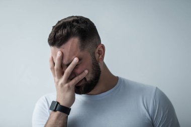 Olumsuz duyguların ifadesi, stres, depresyon, acı çekme ve evdeki psikolojik sorunlar. Kötü, hayal kırıklığına uğramış, üzgün milenyum çocuğu yüzünü ellerle kaplıyor ve gri duvar arkasında ağlıyor.