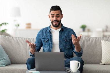 Uzaktan iletişim konsepti. Genç bir Arap 'ın ev ofisinden bilgisayarla iş meselelerini tartışırken görüntülü konuşması. Milenyum Doğulu adam web kamerasından arkadaşlarına ya da iş arkadaşlarına konuşuyor