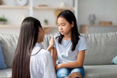 Genç Koreli bir anne, üzgün bir kızı rahatlatıyor, evde konuşuyor ve teselli ediyor, boşluğu kopyalıyor. Asyalı anne, gücenmiş kızına destek oluyor. Aile çatışmaları kavramını çözmek