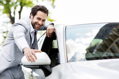 Yeni araba seçmek, galeriden araba almak, kira ve insani duygular. Menajer veya satıcı işi. Gülümseyen bin yıllık yakışıklı beyaz adam modern ulaşım araçlarına bakıyor.