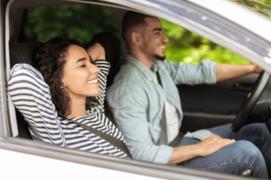 Neşeli bir orta doğu çifti hafta sonu birlikte araba gezintisine çıkıyor, yola bakıyor ve gülümsüyor, tatilin tadını çıkarıyor, yandan bakıyor, dışarıdan çekiliyor. Seyahat, yerel araba yolculuğu, tatil konsepti.