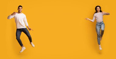 Güzel teklif. Mutlu Orta Doğulu erkek ve kadın, sarı arka planda, tam uzunlukta, panoramada reklam için yer gösteriyorlar.