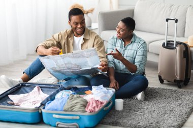 Seyahat Varış Yeri ve Seyrüsefer. Siyah eşler, bir sonraki tatil için Turistik Harita Seçme Ülkesi 'ni tutuyor. Evde bavullarıyla birlikte oturuyorlar. Turizm ve Seyahat Konsepti